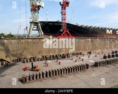 Large oil tanker ship next to a drained dry dock in the port of Antwerp, Belgium Stock Photo