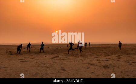 Silhouette Of People , Playing football at the Time of Sunset on a Beach. Stock Photo