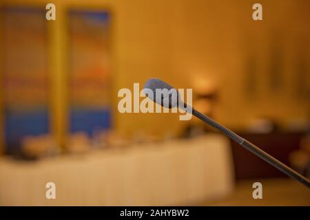 Speech or conference concept. Speaker prepare before speaking to the audience behind the podium focused microphone on the podium and blurred empty Stock Photo