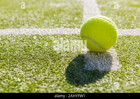 yellow tennis ball in court on green artificial grass, indoor sports concept and sporty lifestyle Stock Photo