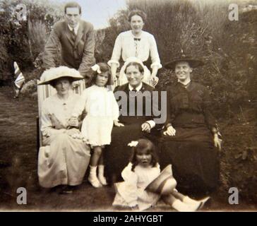 Old vintage black and white photograph of a group of people sat in a garden looking at the camera Stock Photo