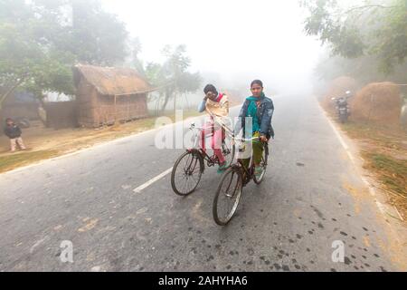 Bangladesh â. “ January 06, 2014: On a foggy winter morning, two young girls are going to school by riding bicycle. at Ranisankail, Thakurgaon.
