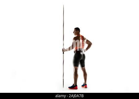 Male athlete practicing in throwing javelin isolated on white background. Professional sportsman, thrower posing confident. Concept of healthy lifestyle, movement, activity, competition. Copyspace. Stock Photo