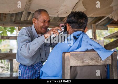 Mandalay, Myanmar - January 11, 2016: An unidentified man cutting hair for the customer in a barber shop. Stock Photo
