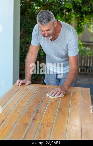 A man working on recycling wood table in the garden, carpenter work. Stock Photo