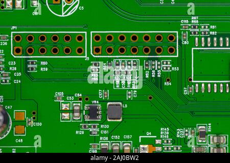 Green electronic circuit board background with visible white numbers, electronic parts and lines Stock Photo