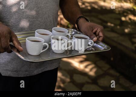 Welcome coffee drink. Closeup male hands carry a tray of coffee. Stock Photo
