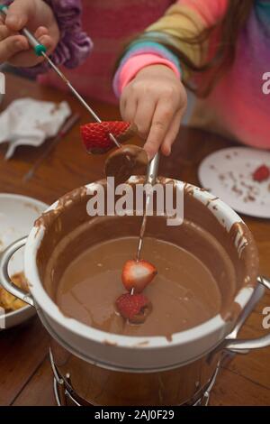 Children eating chocolate fondue Stock Photo