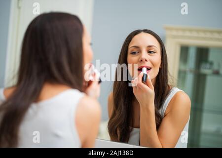 Young woman is applying lipstick in the bathroom. Stock Photo