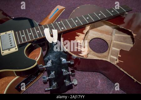 Broken guitars. Pile of smashed electric and acoustic guitar pieces. Frustrated guitarist smashed instrument parts ready for burning or repair. Stock Photo