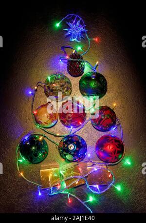 Overhead flat lay of a Christmas tree shape made up from baubles and fairy lights Stock Photo