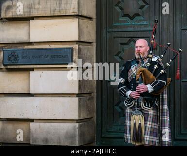 Bagpipe player busker outside High Court of Justiciary, Royal Mile, Edinburgh, Scotland, UK Stock Photo