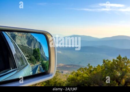Mountain road on a summer sunny day. Panoramic view from above and a car rearview mirror Stock Photo