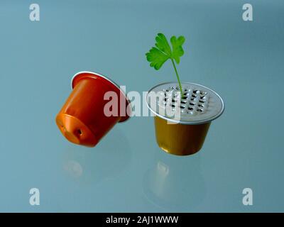 spent aluminum coffee capsules. green leaf. grainy glass surface. recycling concept. modern lifestyle. environment protection. ecological footprint Stock Photo