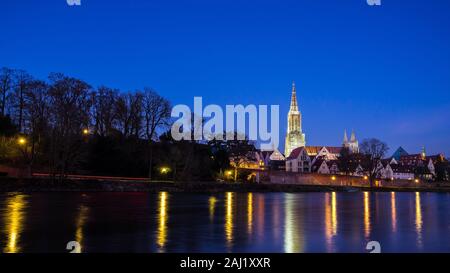 Germany, Ulm city skyline, cityscape and minster cathedral behind water of danube river by night with starry sky Stock Photo