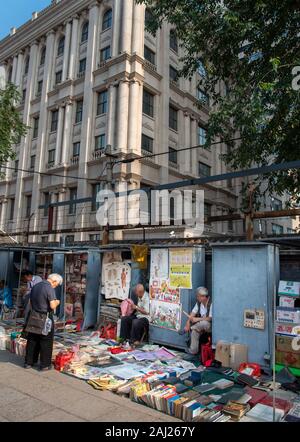 Chinese  Asian man reading and selling antique books at Panjiayuan flea  antique Market in Beijing China. Stock Photo