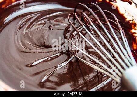 Melted chocolate in bowl with steel whisk Stock Photo