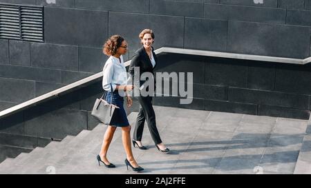 Two women in office wear walking outdoors and talking Stock Photo