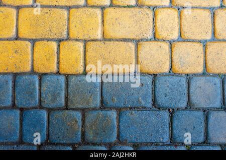 yellow and blue cobbles of pavement texture. stone masonry floor covering. top view of wet grungy background Stock Photo