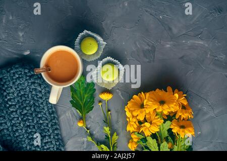 Hot coffee with milk or cream and yellow macaroons on the loft table in a romantic setting with chrysanthemums nearby Stock Photo