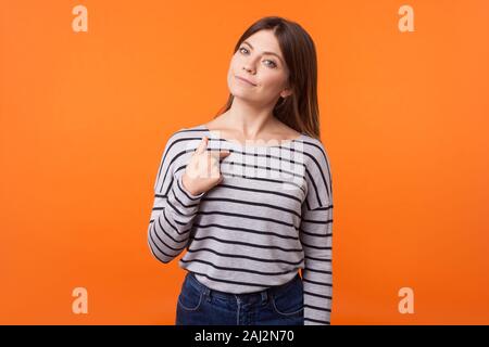 This is me! Portrait of proud young woman with brown hair in long sleeve striped shirt standing, pointing at herself, looking arrogant and selfish. in Stock Photo