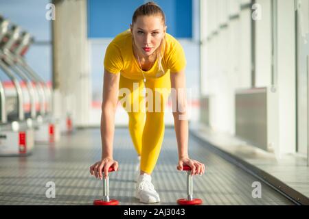 Physically fit woman at the gym with dumbbells ready to strengthen her arms and biceps Stock Photo