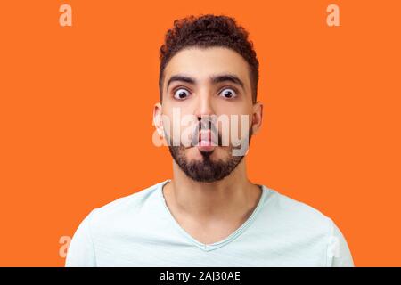 Portrait of funny silly brunette man with beard in casual white t-shirt looking at camera and making fish face with lips and big eyes, fooling around. Stock Photo