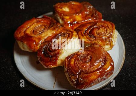 Five homemade sticky buns on a plate with black background Stock Photo