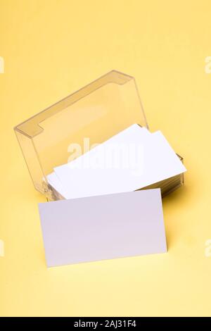 Name cards in white color in card holder with copy space. Personal presentation accessory in close up. Business contacts concept. Business cards stack on yellow background. Stock Photo