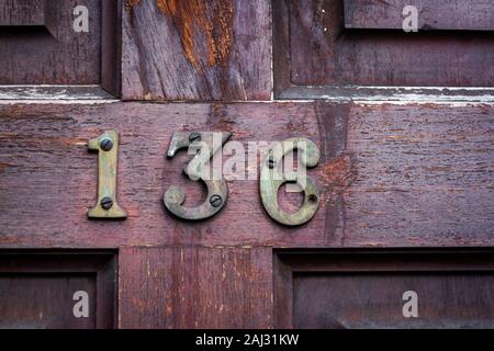 Worn and weathered house number 136 Stock Photo