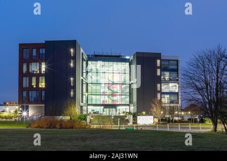 Northampton, Northamptonshire, UK: Lights shining from inside an office building occupied by Avon Products, a global cosmetics company. Stock Photo