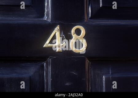 House number 48 on a black wooden fron door Stock Photo