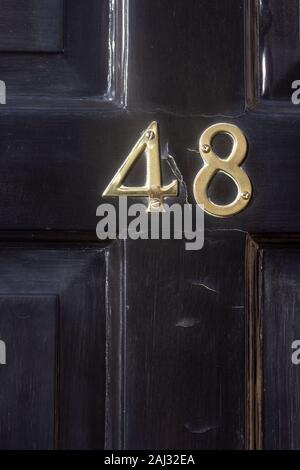 House number 48 on a black wooden fron door Stock Photo