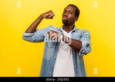 Look at my strength! Portrait of self-confident ambitious man in denim shirt looking arrogant and assertive, pointing at biceps, gesturing I have powe Stock Photo