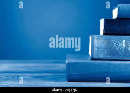 A simple composition from many hardback books, tinted in classic blue color, 2020 trend. I'm going back to school. Copy space Education Stock Photo