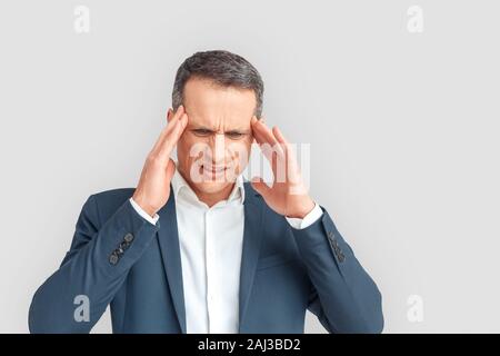 Mature businessman studio standing isolated on white background touching head feeling headache looking down unhappy Stock Photo
