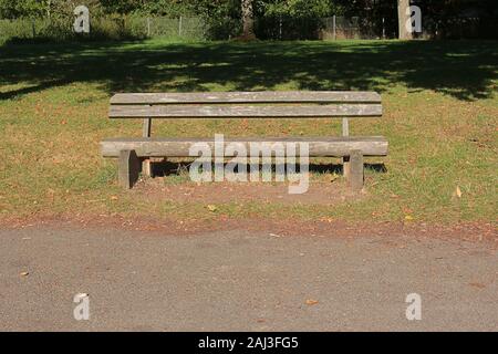 Empty wooden bench in the grass in autumn Stock Photo