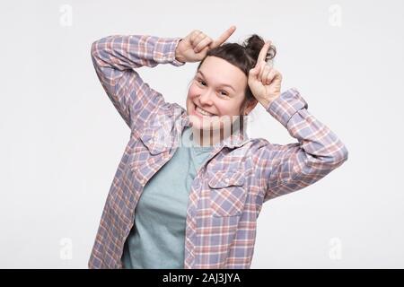 Funny young woman grimacing showing bull horns on head. Positive facial human emotion. Stock Photo