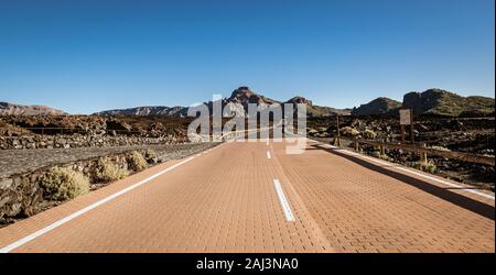Empty road running through volcanic, rocky desert in Teide National Park, Tenerife, Spain. Stock Photo