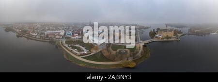 Panorama aerial lake view of Schwerin Castle Palace with heavy fog and haze in the morning