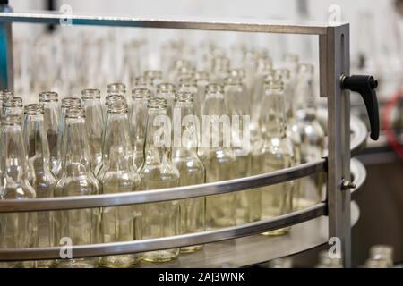 a lot of new white glass empty beer bottles on stainless steel machine, selective focus close up , conveyor belt craft brewery factory microbrewery Stock Photo