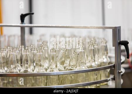 a lot of new white glass empty beer bottles on machine, selective focus close up view, conveyor belt craft brewery factory microbrewery Stock Photo