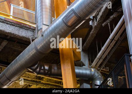 Industrial ventilation system steel ducts and pipes, tubes low angle view, pass through modern factory building interior Stock Photo