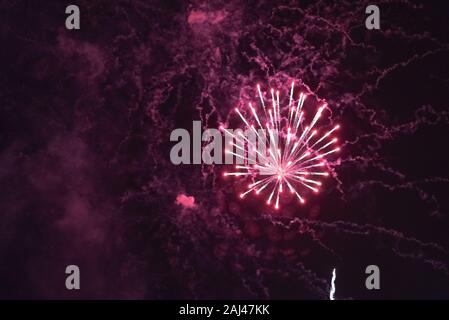 Big red fireworks, with smoke, against the dark sky. Stock Photo