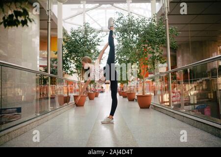 Woman ballerina stands lifting her leg high Stock Photo