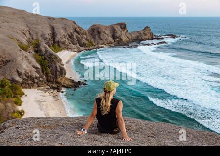 Young woman sitting on rock at sunset Stock Photo
