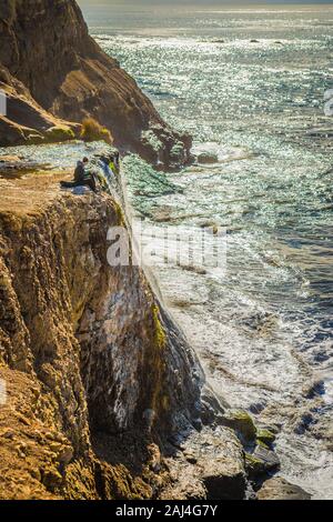 A couple sits at the edge of Alamere Falls on a sunny day in Point Reyes National Seashore, California, USA Stock Photo