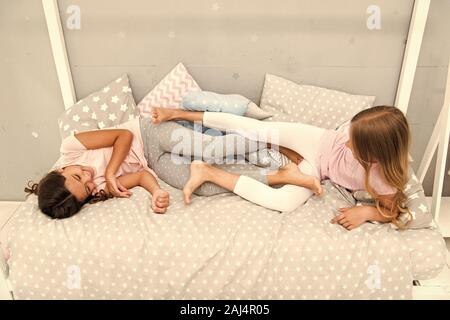having fun together. fun before sleep. best friends. sisters playing in bed. sweet dreams. pajama party in bedroom. childhood happiness. kids friendsh Stock Photo
