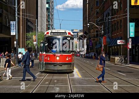 TORONTO, CANADA - 06 27 2016: City dwellers crossing the street in front of an old streetcar on King at Younge st. intersection. Stock Photo