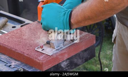 Tile cutter industry equipment. Worker cutting paving tiles for laying on the terrace using circular saw electric Stock Photo